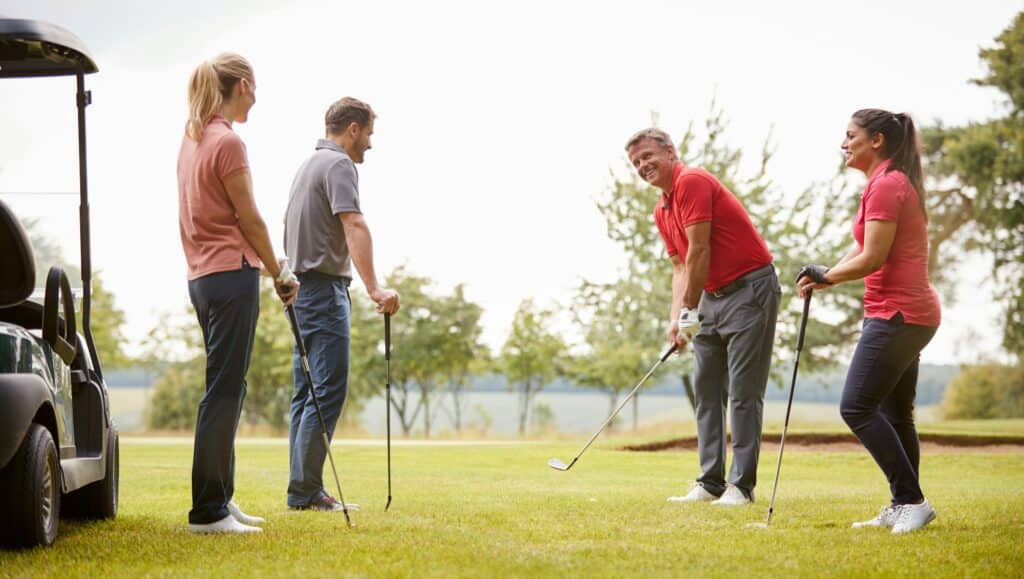Golfprofi demonstriert Golfschlag auf dem Fairway für eine Gruppe von Golfern während des Unterrichts Golfprofi demonstriert Golfschlag auf dem Fairway für eine Gruppe von Golfern während des Unterrichts